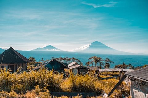 A serene landscape with a mountain in the distance and a few buildings in the foreground.